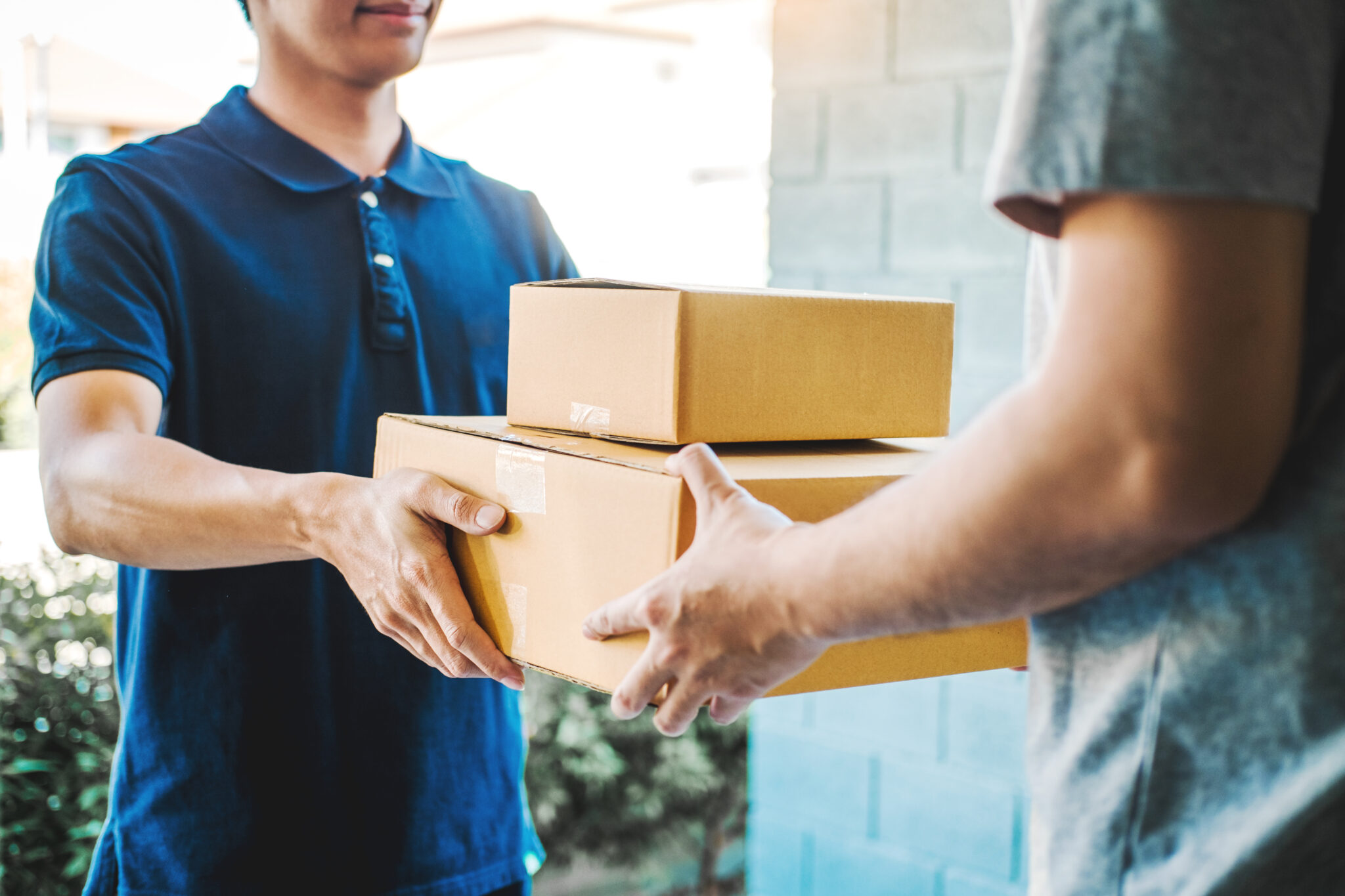 Delivery concept Asian Man hand accepting a delivery boxes from professional deliveryman at home Niet langer onzichtbaar